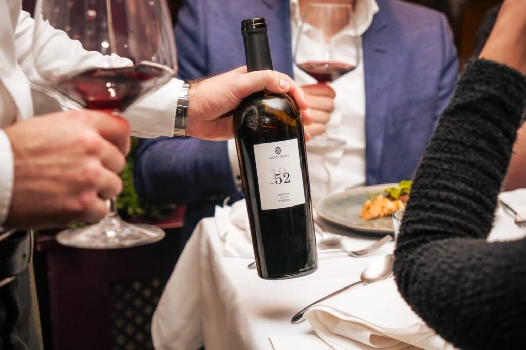 Gasten proosten met rode wijnfles 52 tijdens diner bij Vini di Villani Den Haag